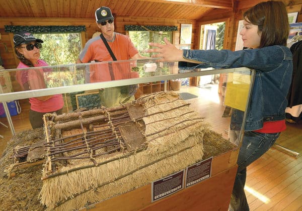 Visitors look at the Darien-Lindgren cabin on display at K'Beq' Cultural Site in Cooper Landing.