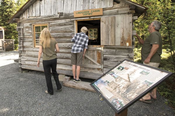 Visitors look at the Darien-Lindgren cabin on display at K'Beq' Cultural Site in Cooper Landing.