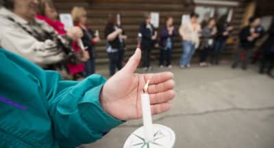 A participant in a candlelight vigil to remember victims of sexual assault shields her tiny flame from the wind outside Tyotka's Elder Center in Old Town Kenai. After a long moment of silence, participants took turns honoring family, friends and themselves. Nearly two dozen people attended the event.