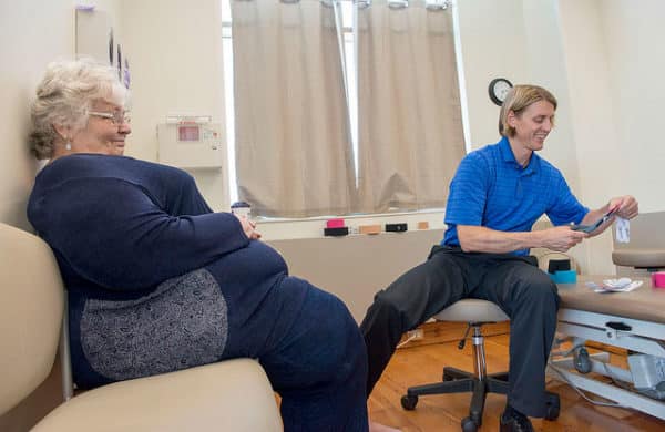 Alexandra "Sasha" Lindgren visits with Physical Therapist Paul Carlson as he affixes strips of Kinesio tape to her left leg at the Dena'ina Wellness Center. Lindgren said the tape has helped her move without pain.