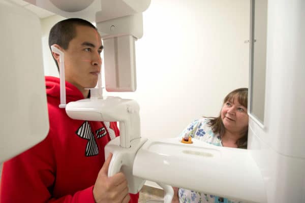 Dental Hygienist Karen Pulley, right, positions Mylon Weems for a panoramic X-ray.