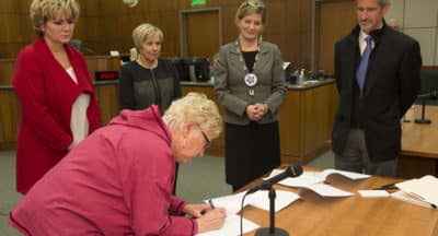 Executive Council Secretary Liisia Blizzard signs the agreement as Kenai Superior Court Judge Anna Moran, Kenaitze Indian Tribe Chief Judge Kim Sweet and Alaska Court System Deputy Director Doug Wooliver, right, wait to sign as Alaska Attorney General Jahna Lindemuth watches, second right.